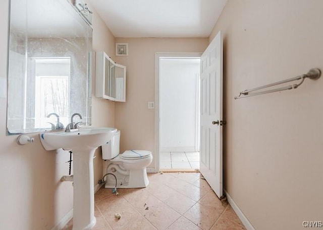 half bathroom with baseboards, toilet, and tile patterned flooring