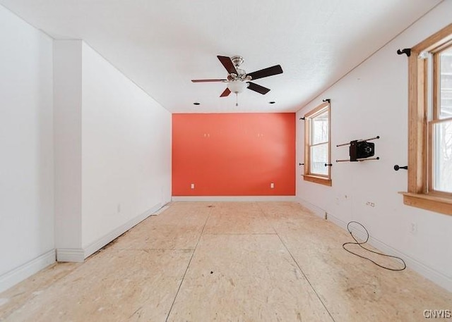 unfurnished room featuring a ceiling fan and baseboards