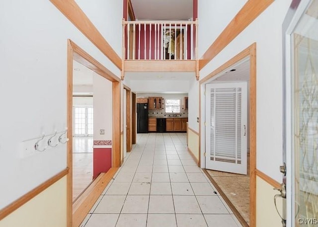 corridor featuring light tile patterned flooring and a high ceiling