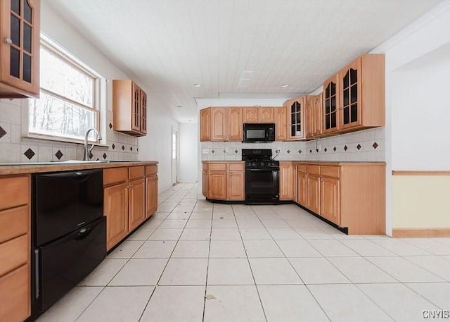 kitchen with decorative backsplash, black appliances, glass insert cabinets, and light countertops