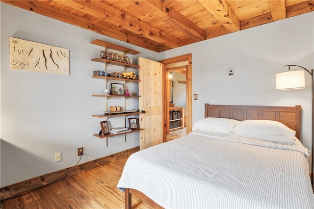 bedroom with beamed ceiling, wood finished floors, baseboards, and wooden ceiling