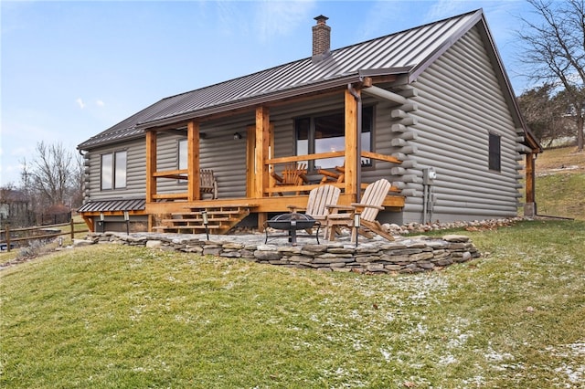 rear view of property with log siding, a yard, metal roof, and a standing seam roof