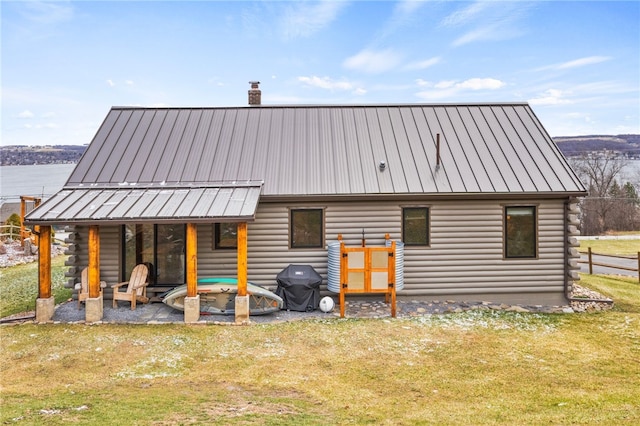 rear view of property with log exterior, a chimney, and a standing seam roof