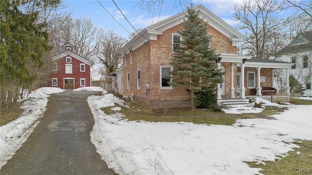 view of front of house with brick siding, a porch, and driveway