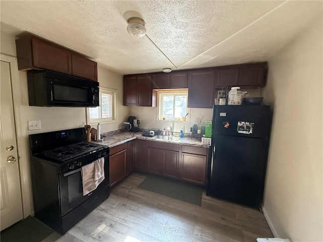 kitchen with black appliances, light wood-style flooring, light stone countertops, and a textured ceiling