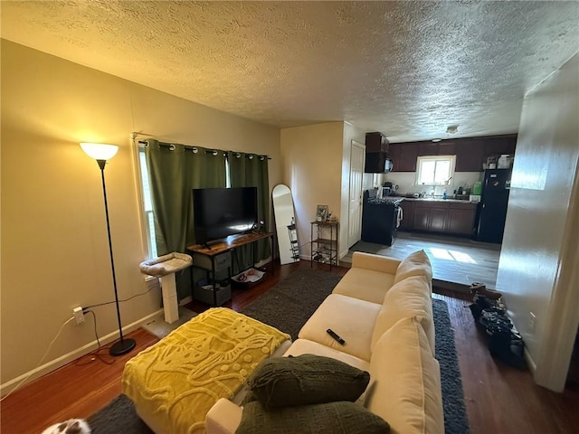 living room featuring baseboards, a textured ceiling, and light wood finished floors