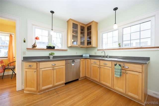 kitchen with a sink, dark countertops, dishwasher, and light wood finished floors