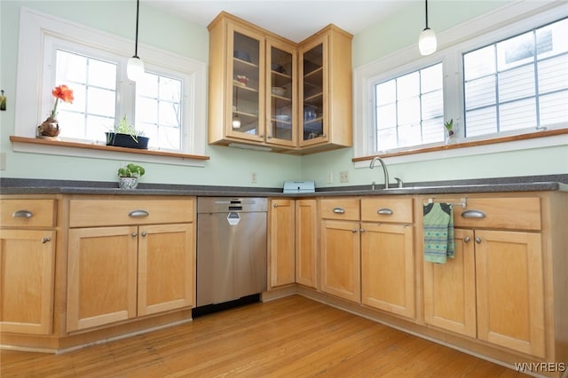 kitchen with dark countertops, glass insert cabinets, a healthy amount of sunlight, and light wood finished floors