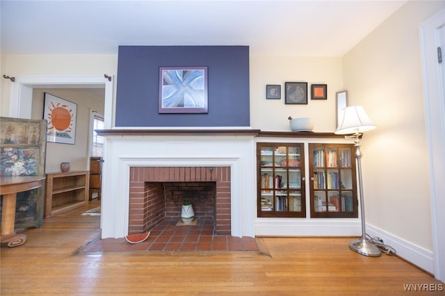 unfurnished living room featuring baseboards, wood finished floors, and a fireplace