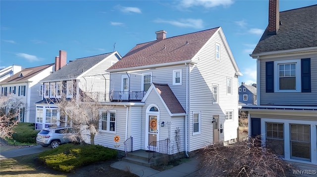 rear view of house featuring a balcony and roof with shingles