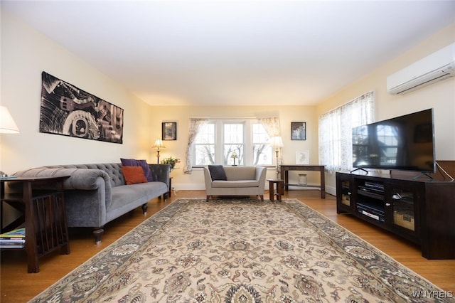 living room featuring baseboards, wood finished floors, and a wall unit AC