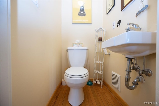 bathroom with visible vents, baseboards, toilet, and wood finished floors