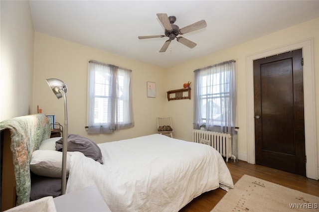 bedroom with a ceiling fan, radiator heating unit, and wood finished floors