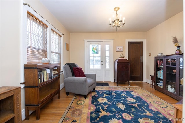 sitting room featuring an inviting chandelier, wood finished floors, and baseboards