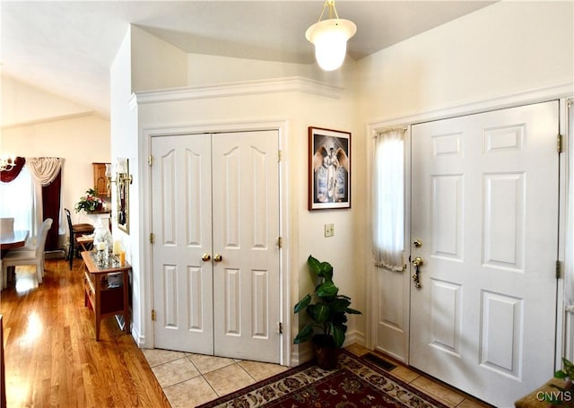 entryway with light tile patterned flooring and vaulted ceiling