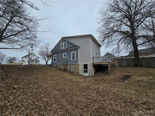 rear view of house with a wooden deck, stairs, and fence