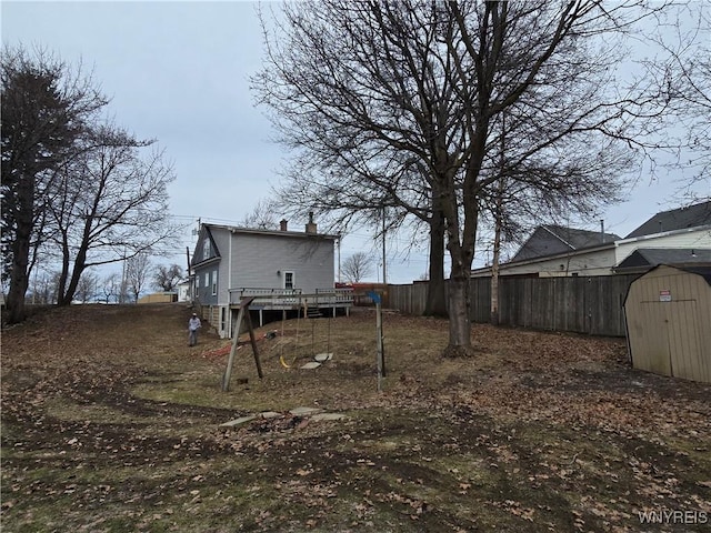 view of yard featuring an outbuilding, a storage unit, fence, and a wooden deck