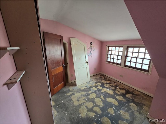 interior space with baseboards, lofted ceiling, and concrete flooring