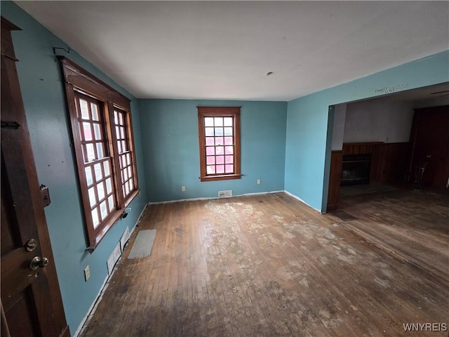 unfurnished living room featuring hardwood / wood-style floors, a fireplace, visible vents, and baseboards