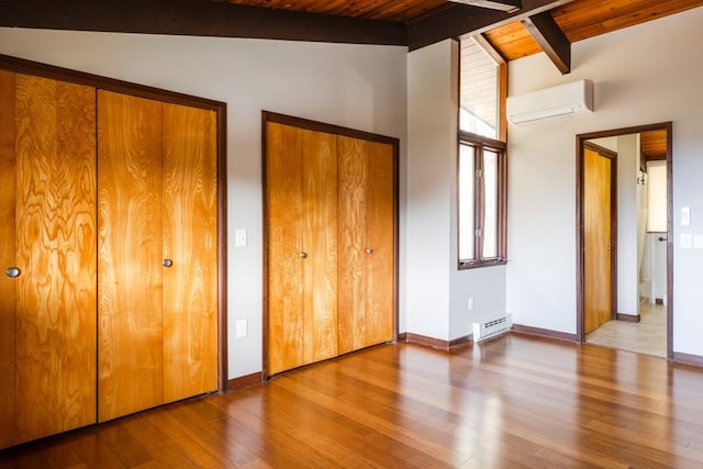 unfurnished bedroom featuring lofted ceiling with beams, multiple windows, multiple closets, and an AC wall unit