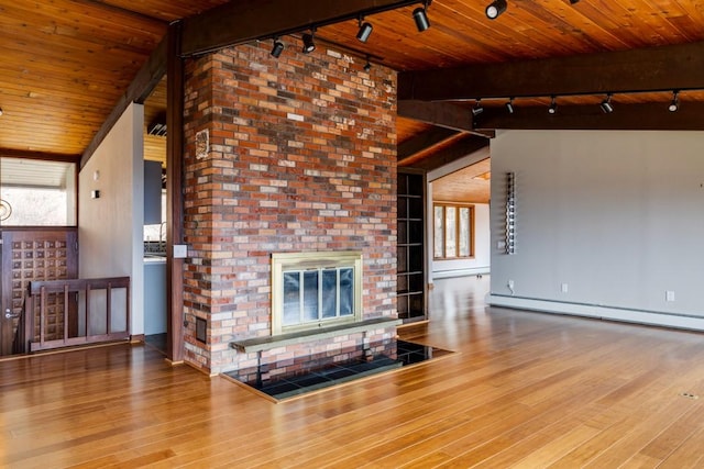 unfurnished living room featuring wood finished floors, wooden ceiling, rail lighting, a baseboard radiator, and a brick fireplace