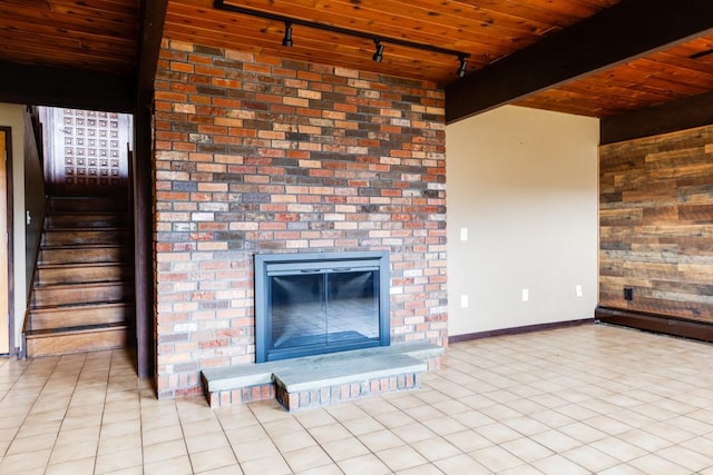 unfurnished living room featuring tile patterned flooring, a brick fireplace, stairs, beam ceiling, and wooden ceiling