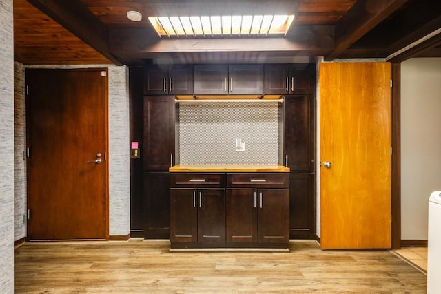 interior space with backsplash, beam ceiling, and light wood-style floors