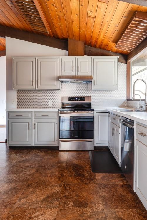 kitchen featuring a sink, stainless steel appliances, under cabinet range hood, wooden ceiling, and tasteful backsplash