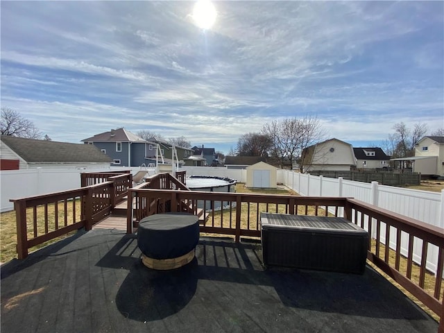 wooden terrace with an outdoor structure, a storage unit, a fenced backyard, and a residential view