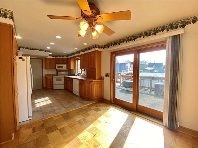 kitchen with baseboards, white appliances, and brown cabinetry