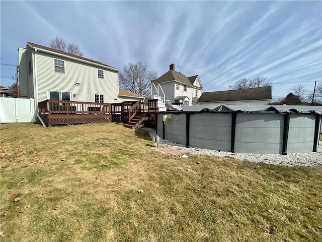 view of yard with an outdoor pool, a wooden deck, and fence