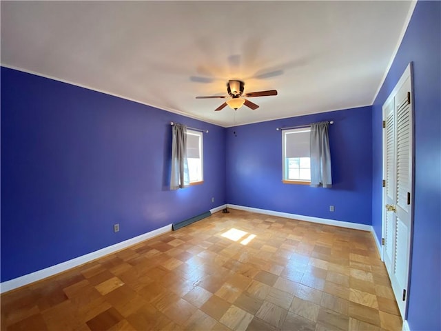 spare room featuring plenty of natural light, ceiling fan, and baseboards