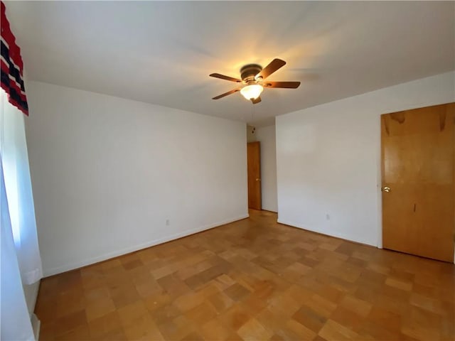 empty room featuring a ceiling fan and baseboards