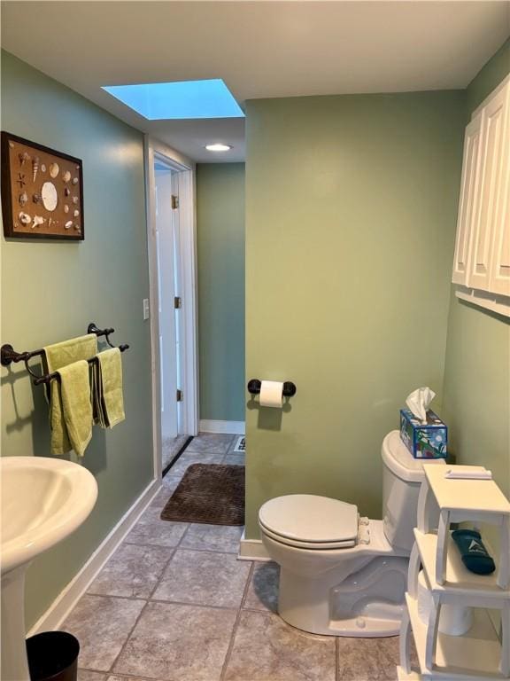 half bath with a skylight, toilet, and baseboards