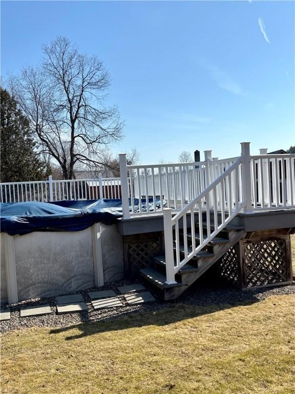 deck featuring a covered pool, stairway, and a yard