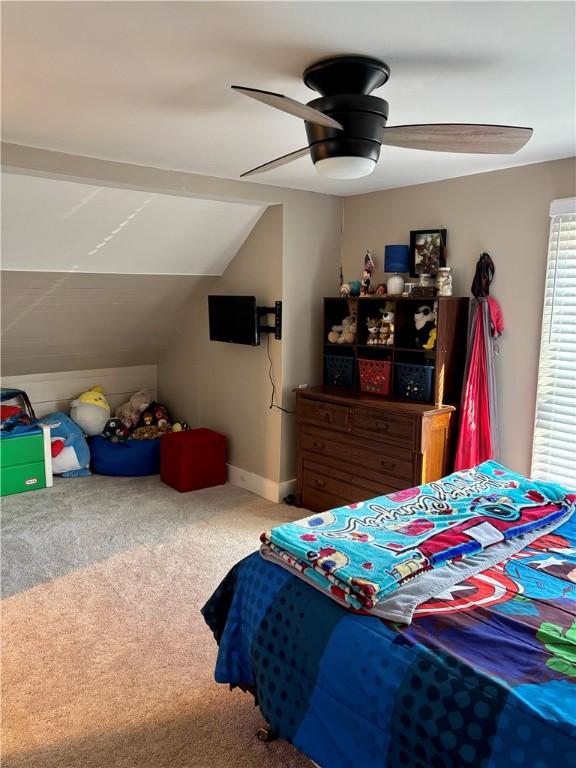 carpeted bedroom with vaulted ceiling and a ceiling fan