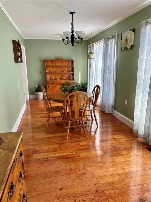 dining area featuring light wood-style floors, baseboards, crown molding, and an inviting chandelier