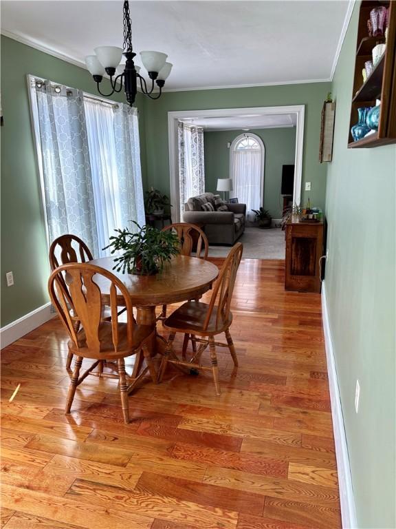 dining area featuring a notable chandelier, baseboards, light wood-style floors, and ornamental molding