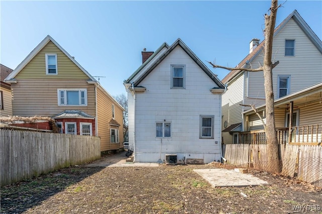 back of property with central AC unit, a chimney, and fence