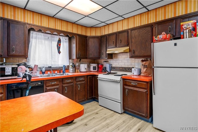 kitchen with white appliances, a sink, light countertops, dark brown cabinetry, and under cabinet range hood