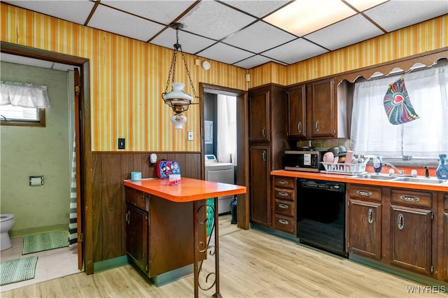 kitchen with dishwasher, washer / dryer, light countertops, and a wainscoted wall