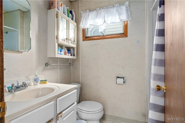 bathroom with vanity, curtained shower, toilet, and wallpapered walls