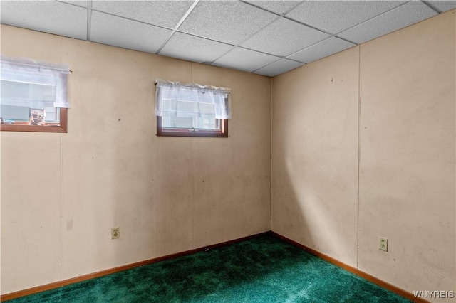 empty room featuring a drop ceiling and dark carpet