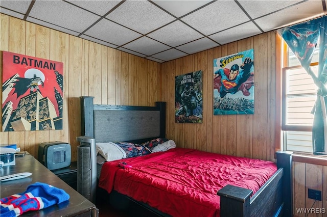 bedroom featuring wooden walls and a paneled ceiling