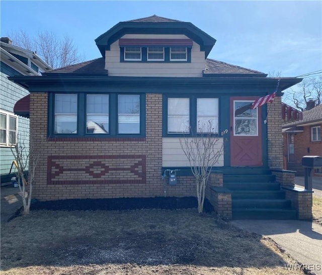 view of front of house with brick siding, roof with shingles, and entry steps