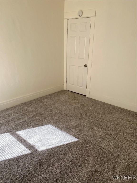 carpeted empty room featuring baseboards