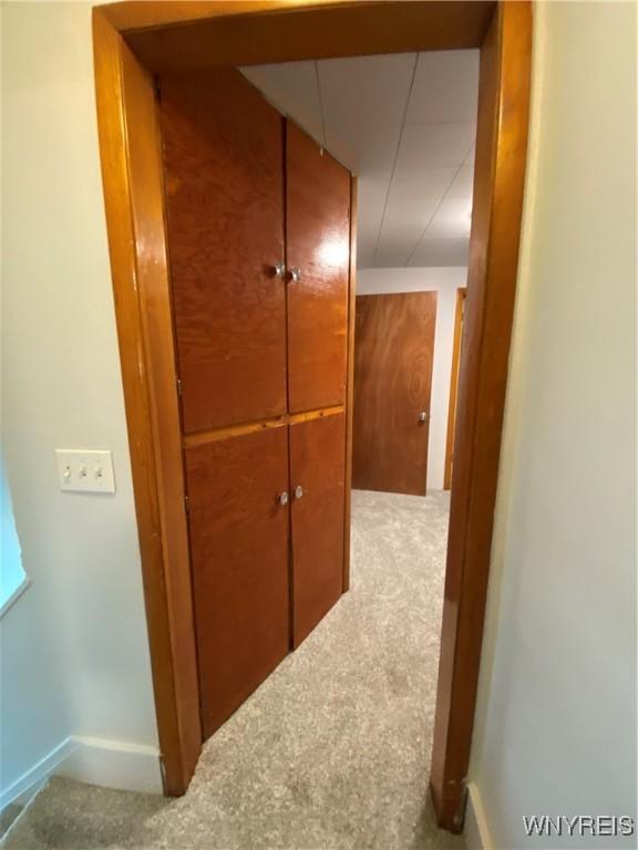 hall featuring carpet flooring and baseboards