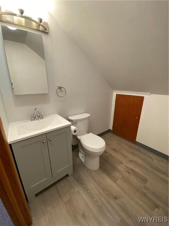 bathroom featuring vaulted ceiling, toilet, vanity, and wood finished floors