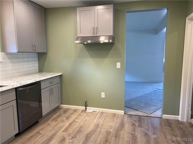 kitchen featuring light wood-style flooring, gray cabinets, decorative backsplash, under cabinet range hood, and stainless steel dishwasher