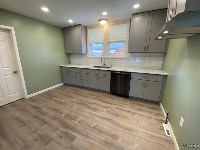 kitchen with backsplash, under cabinet range hood, dishwashing machine, gray cabinets, and a sink